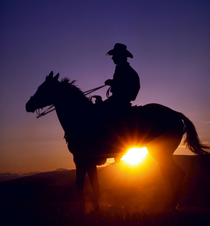Cowboy on horse at sunrise.